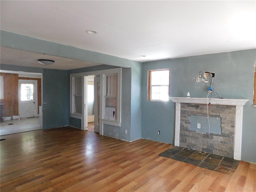 A living room with hardwood floors, a stone fireplace, and a doorway to another room — 6400 12TH STREET, ZEPHYRHILLS, FL