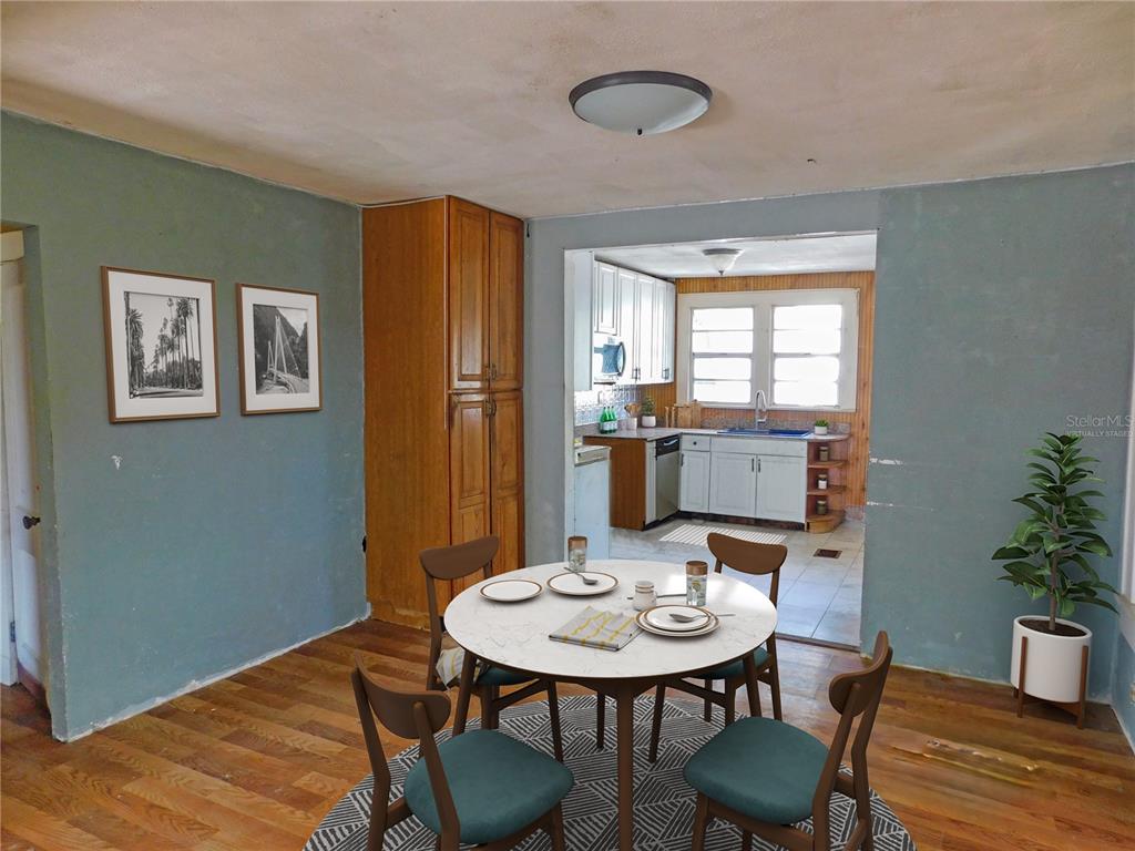 A dining area with wood floors and a round table leads into a white kitchen — 6400 12TH STREET, ZEPHYRHILLS, FL