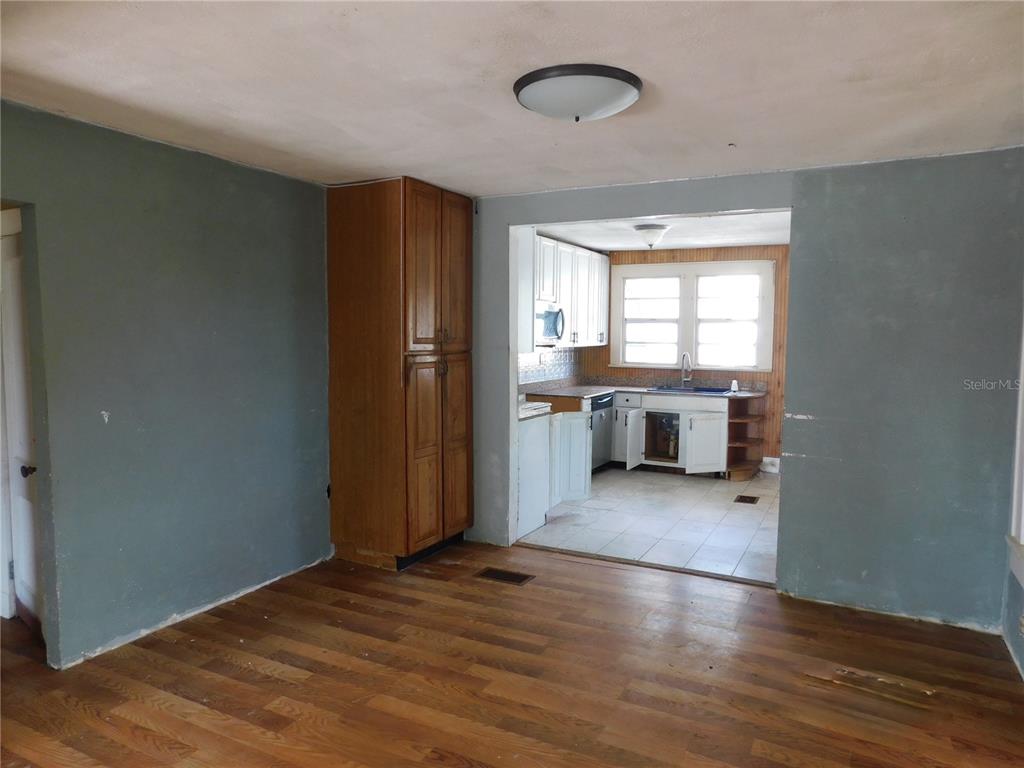 A view of a living room with wood flooring leading into a kitchen with white cabinets — 6400 12TH STREET, ZEPHYRHILLS, FL