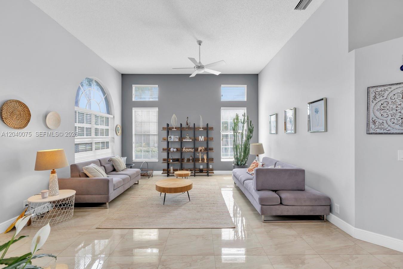A living room features two gray sofas, a central coffee table, and a tall shelving unit — 19700 Dinner Key Dr, Boca Raton FL 33498, BOCA RATON, FL