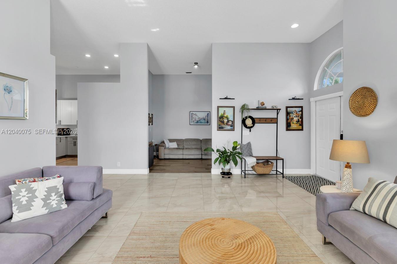 A spacious living area features light gray walls, tile flooring, and a view into another room — 19700 Dinner Key Dr, Boca Raton FL 33498, BOCA RATON, FL
