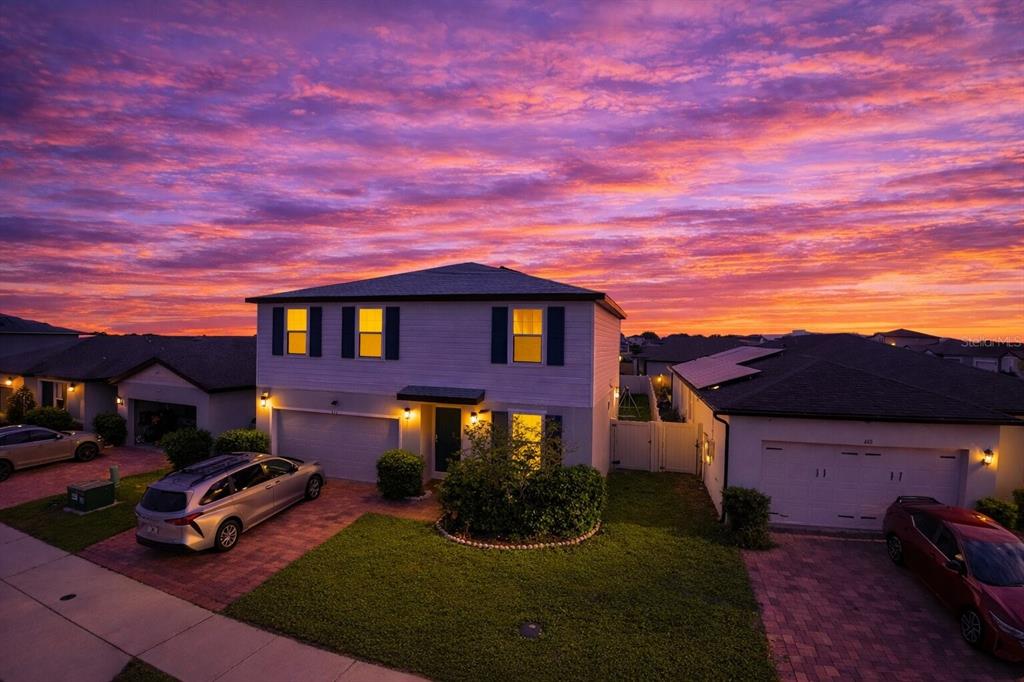 An aerial view of a two-story suburban house at sunset with two cars parked outside — 441 MCKENNA DRIVE, WINTER HAVEN, FL
