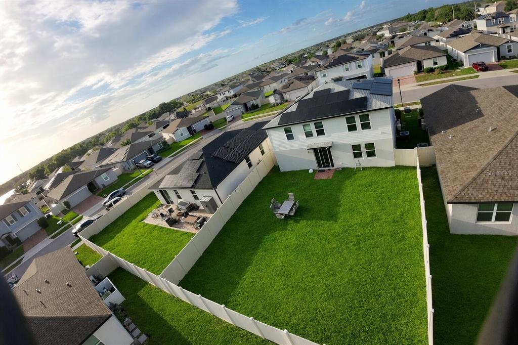 An aerial view shows a suburban neighborhood with houses featuring solar panels and fenced yards — 441 MCKENNA DRIVE, WINTER HAVEN, FL