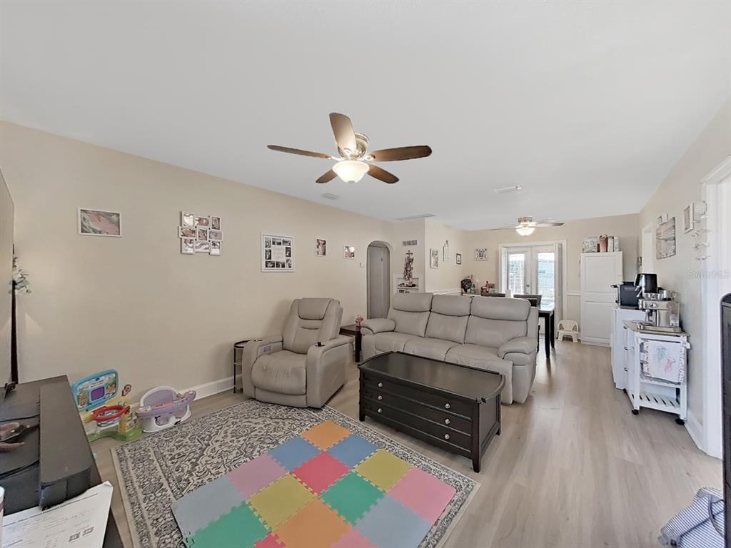 A living room with light wood floors, a beige sofa, a recliner, and colorful floor mats — 2730 EDWARDS AVENUE S, ST PETERSBURG, FL