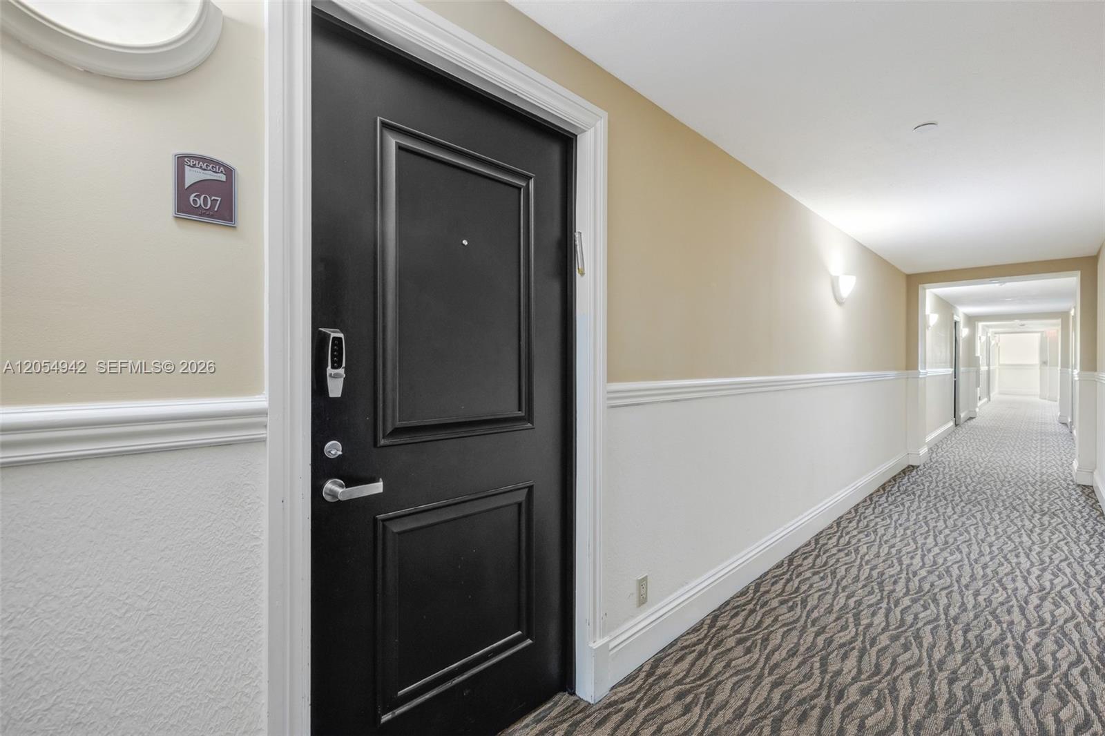 A black apartment door with a keypad lock is located in a carpeted hallway — 9499 Collins Ave # 607, Surfside FL 33154, SURFSIDE, FL