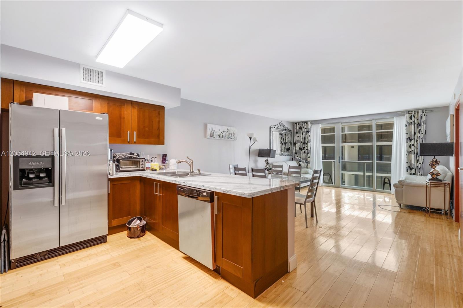 This open-concept kitchen features wood cabinetry, stainless steel appliances, and a marble-topped island — 9499 Collins Ave # 607, Surfside FL 33154, SURFSIDE, FL