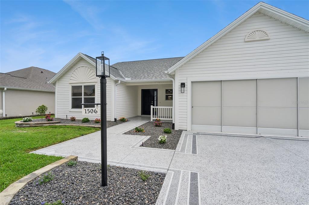 A single-story house with white siding, a two-car garage, and a decorative concrete driveway — 1506 DELLANO WAY, THE VILLAGES, FL