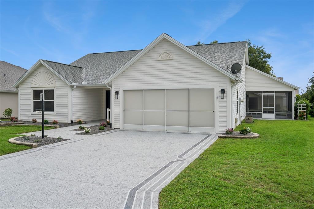 A single-story house with white siding, a multi-car garage, and a screened-in side porch — 1506 DELLANO WAY, THE VILLAGES, FL