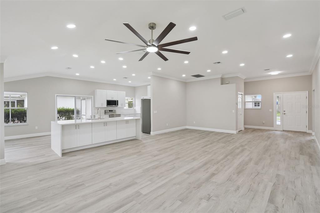 A spacious open-concept kitchen and living area features light wood-look flooring and recessed lighting — 1506 DELLANO WAY, THE VILLAGES, FL