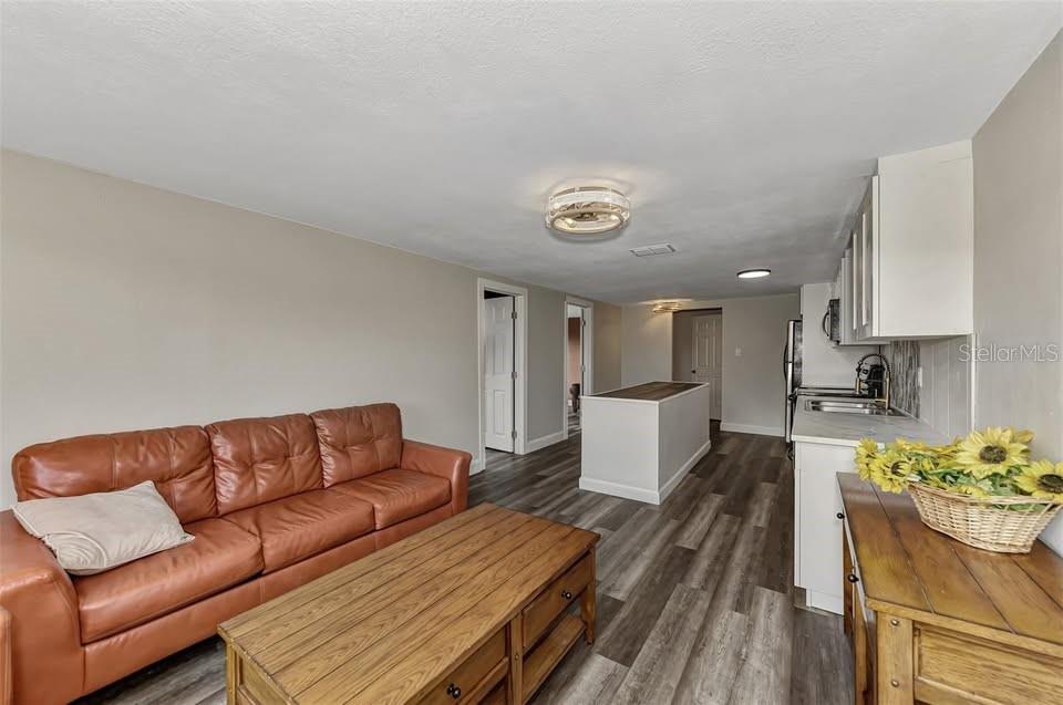 A living room with a brown leather sofa, wood coffee table, and adjacent kitchen area — 304 SAN CARLOS AVENUE UNIT B, NORTH PORT, FL