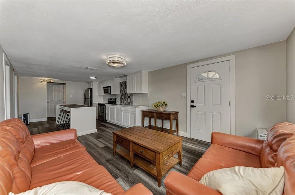 A living room with two orange leather sofas faces a kitchen with white cabinets — 304 SAN CARLOS AVENUE UNIT B, NORTH PORT, FL