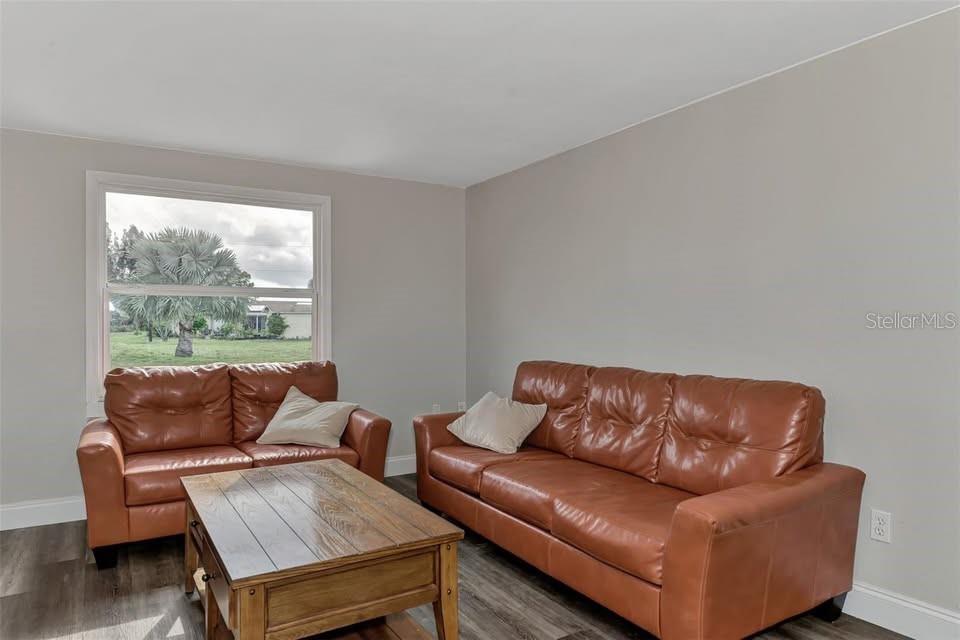 A living room features two brown leather sofas, a wooden coffee table, and a large window — 304 SAN CARLOS AVENUE UNIT B, NORTH PORT, FL