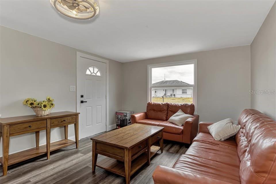 A living room features wood-look flooring, two brown leather sofas, a coffee table, and a console — 304 SAN CARLOS AVENUE UNIT B, NORTH PORT, FL