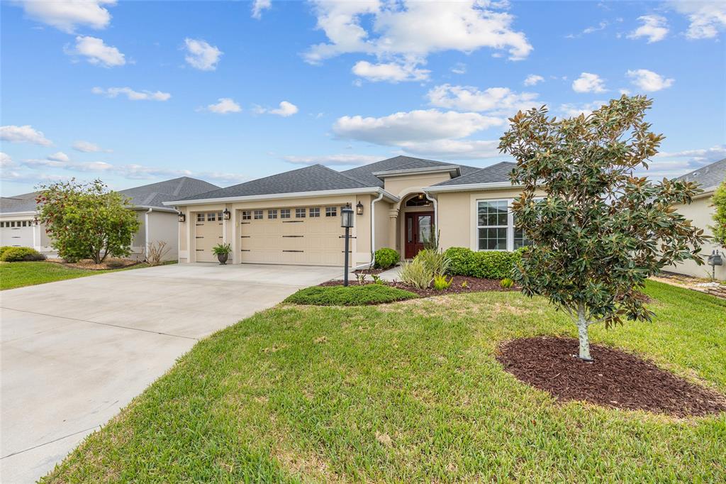 A covered entryway features a red front door with sidelights and a hanging lantern light — 5791 HENRY LOOP, THE VILLAGES, FL