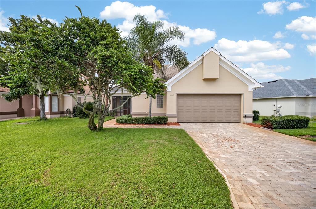 A single-story house with a beige exterior, a two-car garage, and a paved driveway — 30089 ISLAND CLUB DRIVE, DEER ISLAND, FL