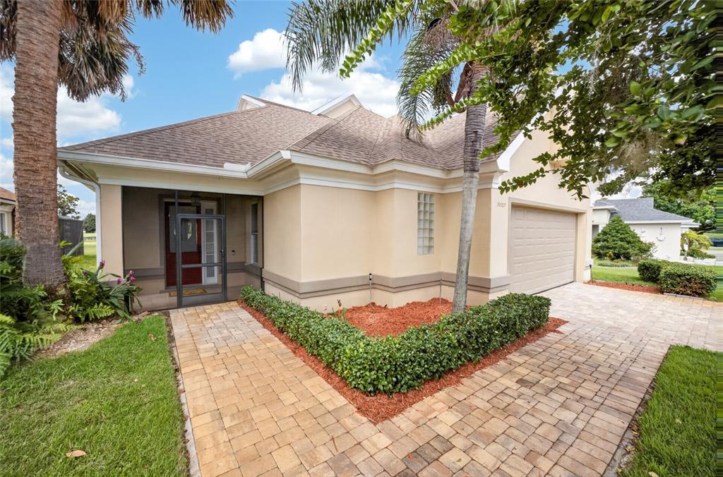 A single-story house with a beige stucco exterior, a paved walkway, and a two-car garage — 30089 ISLAND CLUB DRIVE, DEER ISLAND, FL