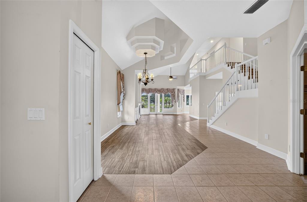 An open-concept living area features wood-look flooring, a vaulted ceiling, and a staircase — 30089 ISLAND CLUB DRIVE, DEER ISLAND, FL