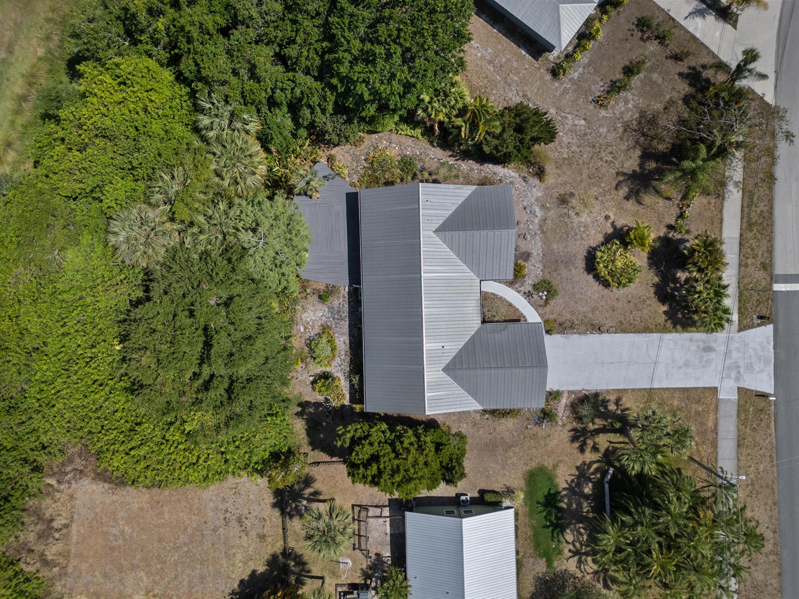 An aerial view shows a house with a gray metal roof surrounded by lush trees — 700 NW North River Drive, Stuart FL 34994, STUART, FL