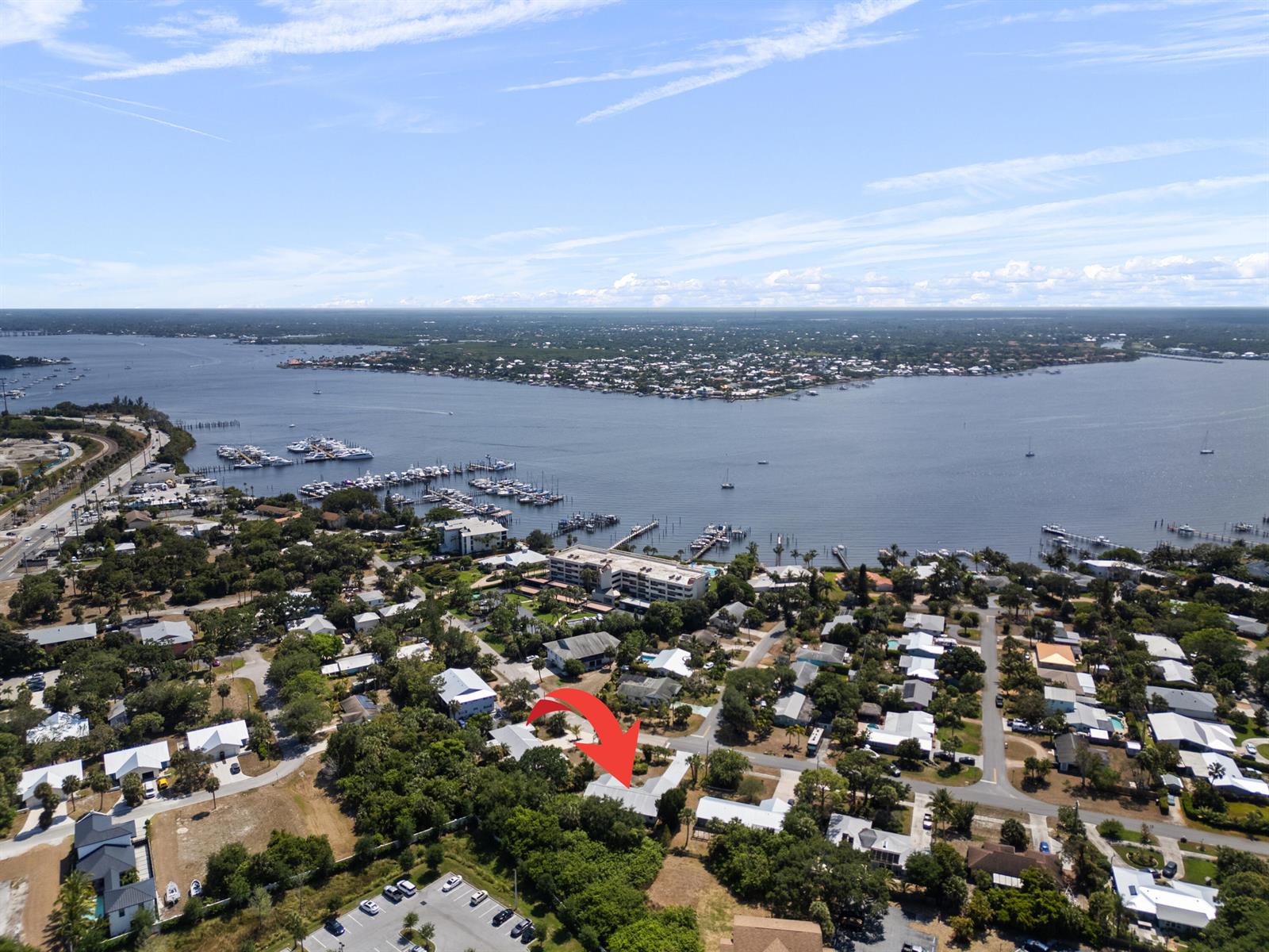 An aerial view shows a residential neighborhood near a bay with a red arrow pointing to a house — 700 NW North River Drive, Stuart FL 34994, STUART, FL