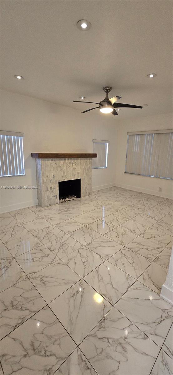 A living room features a tiled fireplace, marble-patterned flooring, and a ceiling fan — 455 NE 131st St # 1, North Miami FL 33161, NORTH MIAMI, FL
