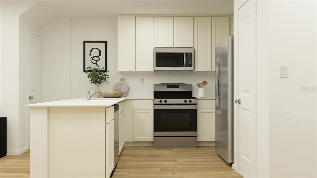 This kitchen features white cabinets, stainless steel appliances, a center island, and light wood flooring — 3048 CAPTAIN JAX WAY, WINTER HAVEN, FL