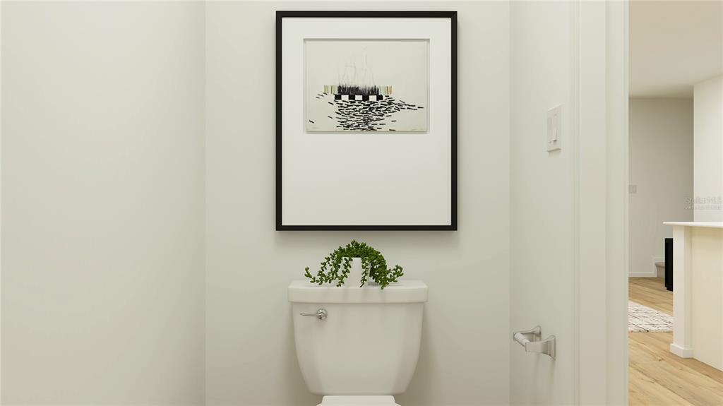 A modern half bathroom features a white toilet, a small plant, and framed wall art — 3048 CAPTAIN JAX WAY, WINTER HAVEN, FL