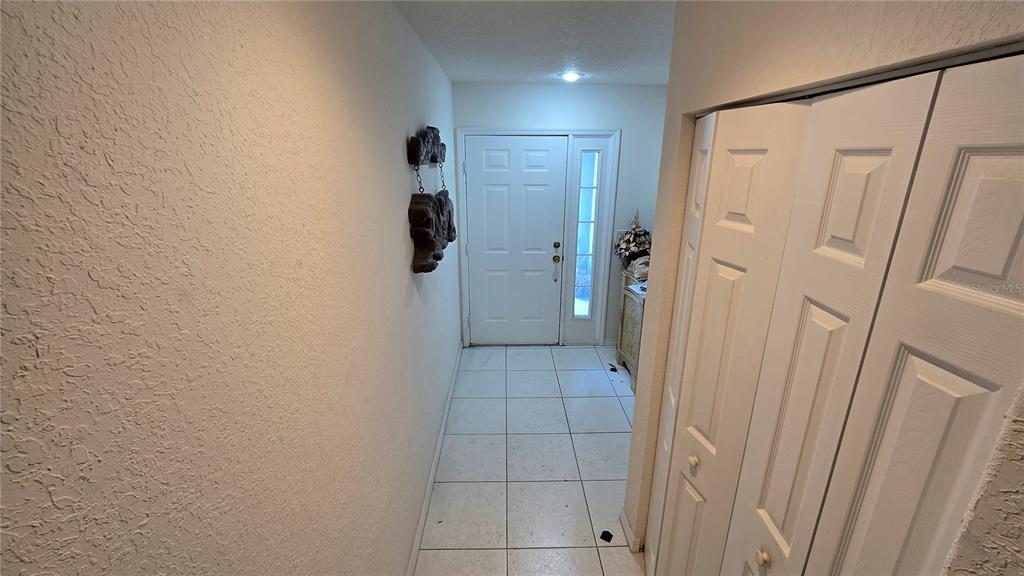 A tiled entryway features a white front door with a sidelight and a bi-fold closet — 521 PINELLAS BAYWAY S UNIT 206, TIERRA VERDE, FL