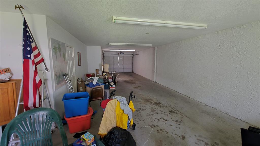 A long, narrow garage with a concrete floor, white walls, and fluorescent ceiling lights — 521 PINELLAS BAYWAY S UNIT 206, TIERRA VERDE, FL