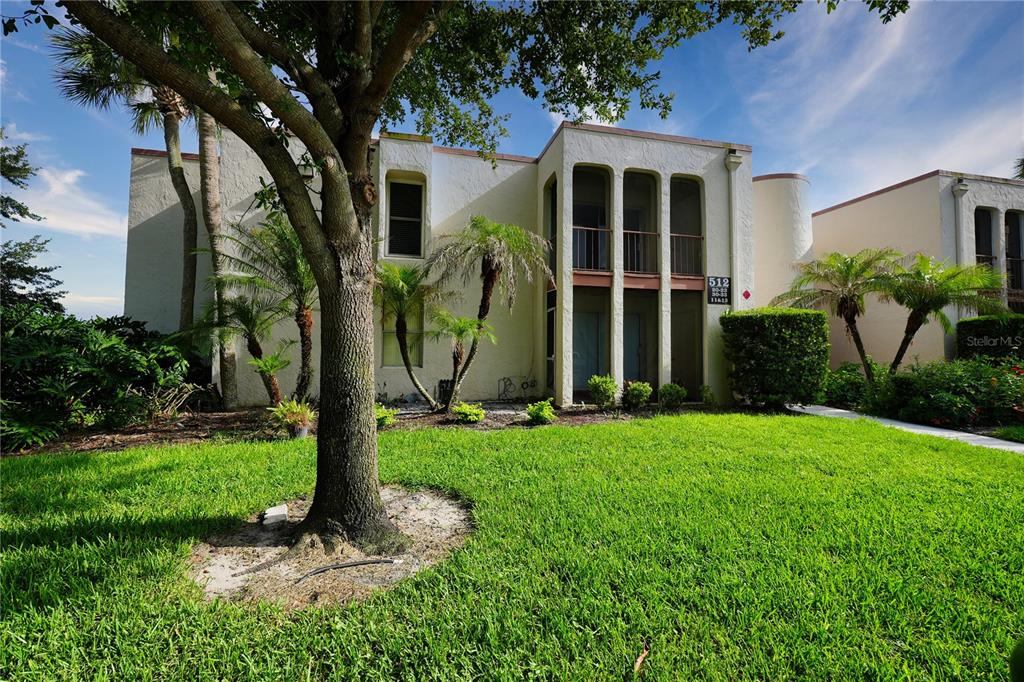 A two-story stucco apartment building features arched entryways and a large tree in the foreground — 512 ORANGE DRIVE UNIT 20, ALTAMONTE SPRINGS, FL