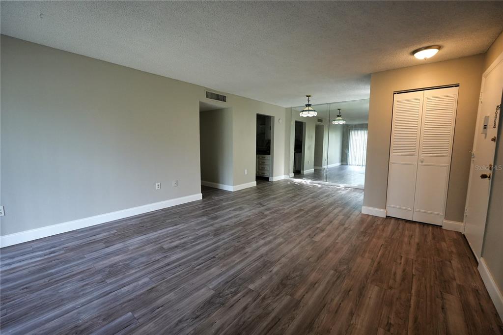 An empty living area features gray wood-look flooring, white trim, and a mirrored wall — 512 ORANGE DRIVE UNIT 20, ALTAMONTE SPRINGS, FL