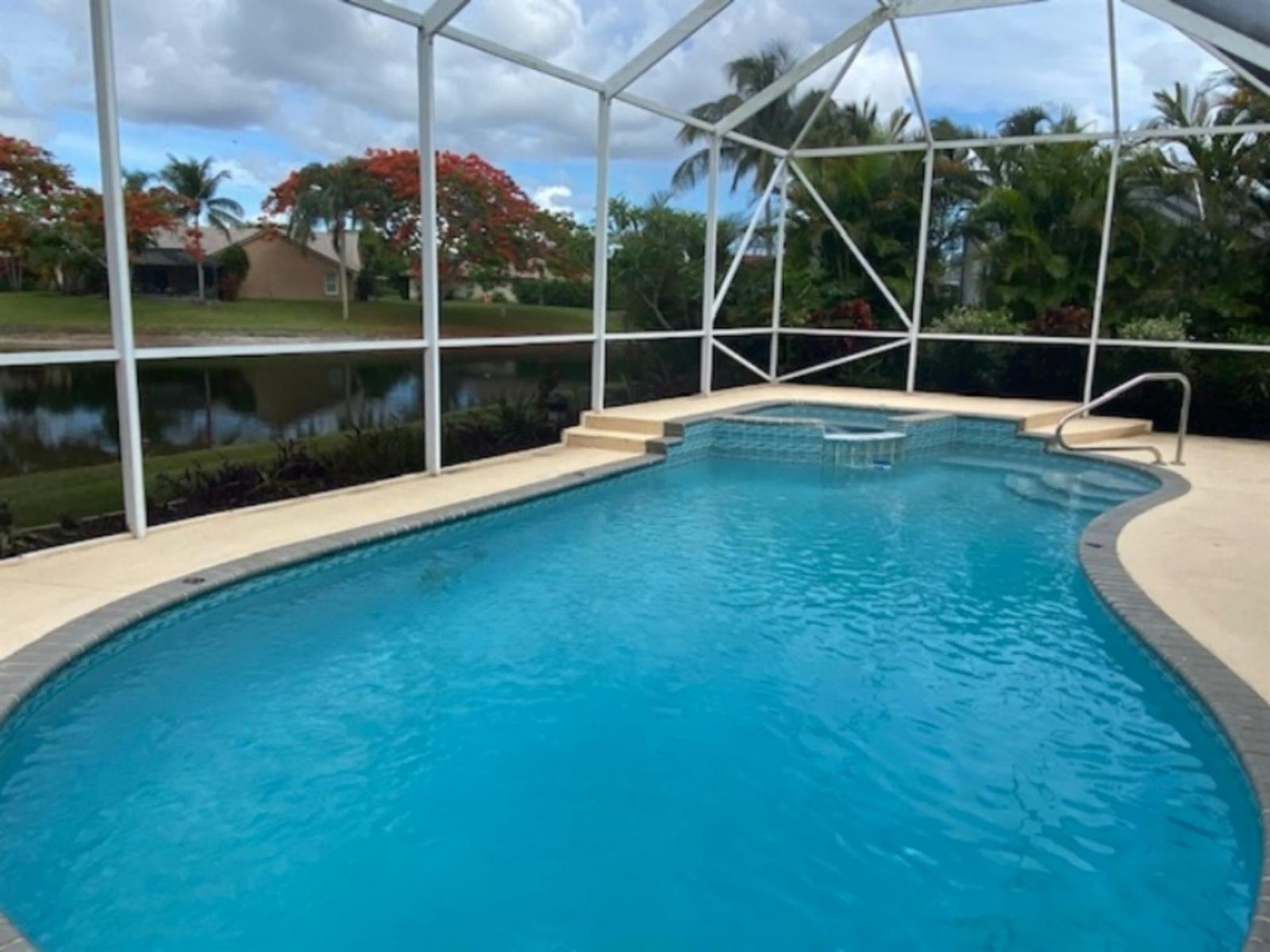 A screened-in swimming pool and spa overlook a lake with trees in the background — 18756 Cape Sable Drive, Boca Raton FL 33498, BOCA RATON, FL