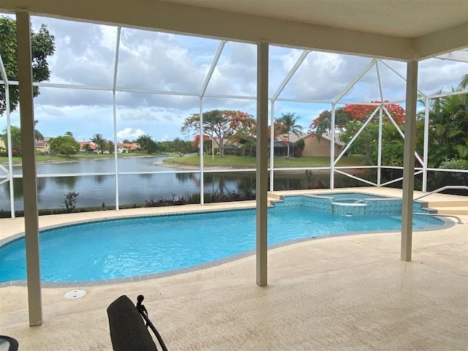 A screened-in patio overlooks a swimming pool, a hot tub, and a lake — 18756 Cape Sable Drive, Boca Raton FL 33498, BOCA RATON, FL