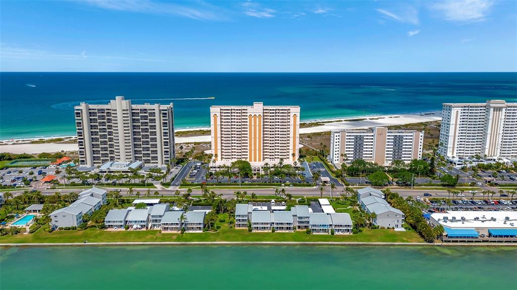 An aerial view of several beachfront high-rise condominiums and low-rise buildings along a coastal shoreline — 1270 GULF BOULEVARD UNIT 1003, CLEARWATER, FL