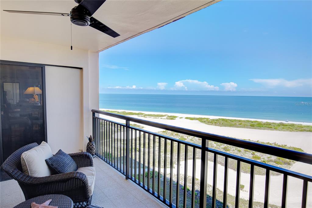 A balcony with a wicker chair overlooks a sandy beach and the ocean — 1270 GULF BOULEVARD UNIT 1003, CLEARWATER, FL