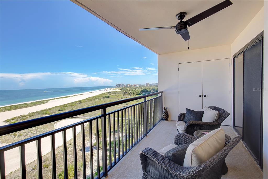 A balcony with wicker chairs, a ceiling fan, and a view of the beach — 1270 GULF BOULEVARD UNIT 1003, CLEARWATER, FL