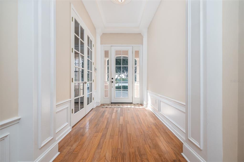 A bright entryway features hardwood floors, white wainscoting, and a glass-paneled front door — 314 W LAKE VICTORIA CIRCLE, DELAND, FL