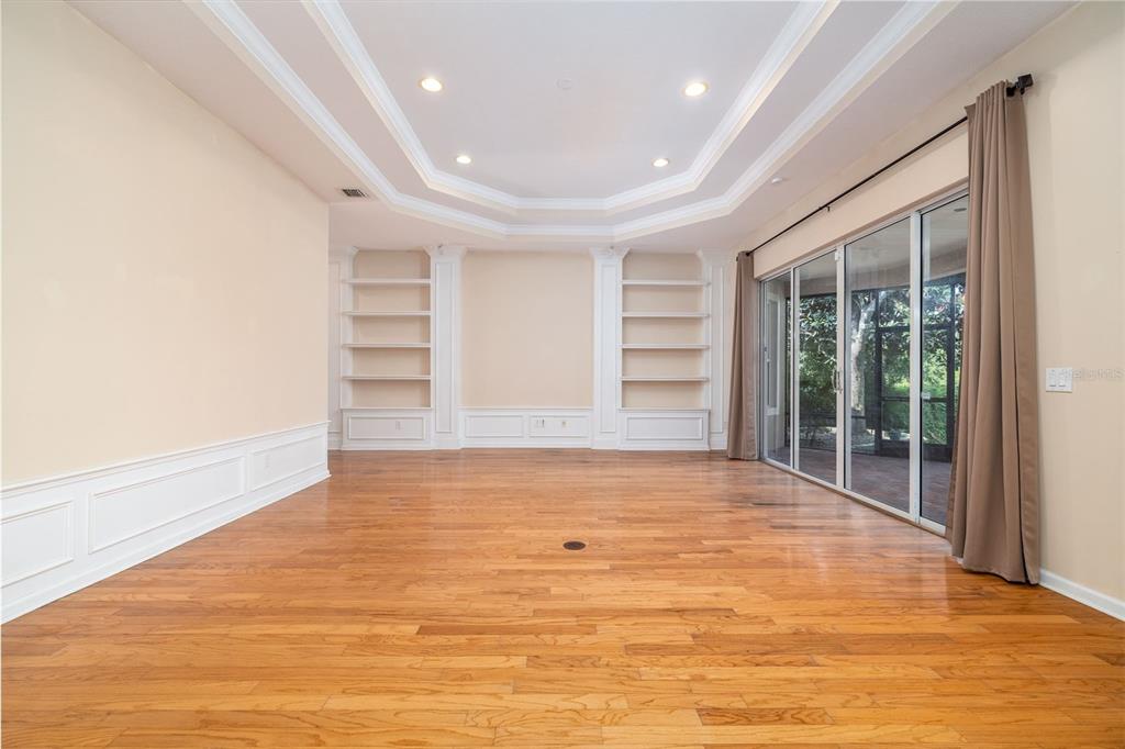 An empty room with hardwood floors, built-in shelving, a tray ceiling, and sliding glass doors — 314 W LAKE VICTORIA CIRCLE, DELAND, FL