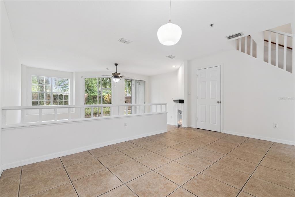 A living room with tile flooring, a half-wall, a ceiling fan, and a staircase — 685 SCARLET OAK CIRCLE UNIT 109, ALTAMONTE SPRINGS, FL