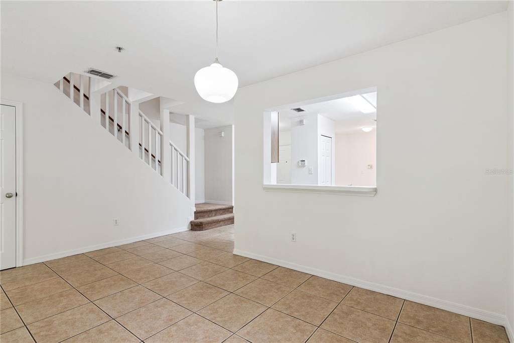 A dining area features tan tile flooring, a white pendant light, and a pass-through window — 685 SCARLET OAK CIRCLE UNIT 109, ALTAMONTE SPRINGS, FL