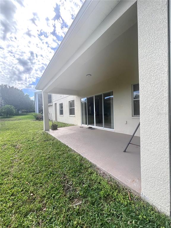 A covered concrete patio extends from the rear of a house with sliding glass doors — 818 PECORI TERRACE, OCOEE, FL