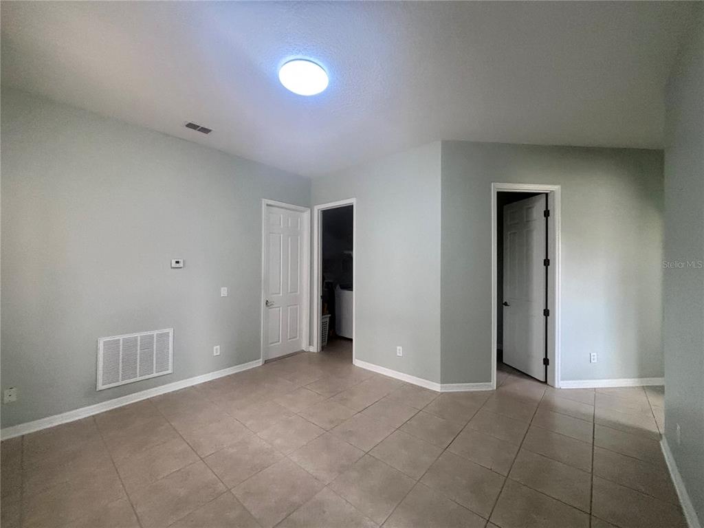 A room with light green walls, tile flooring, a ceiling light, and three doorways — 818 PECORI TERRACE, OCOEE, FL