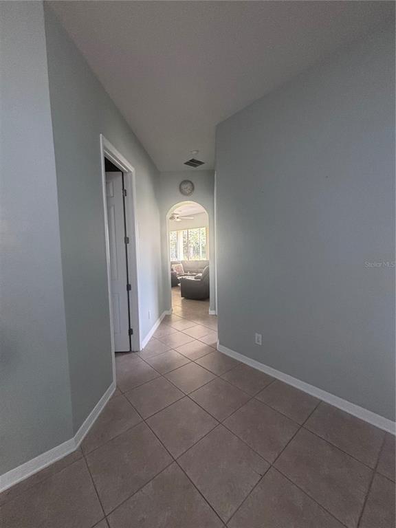 A tiled hallway leads through an arched doorway into a living room with light-colored walls — 818 PECORI TERRACE, OCOEE, FL