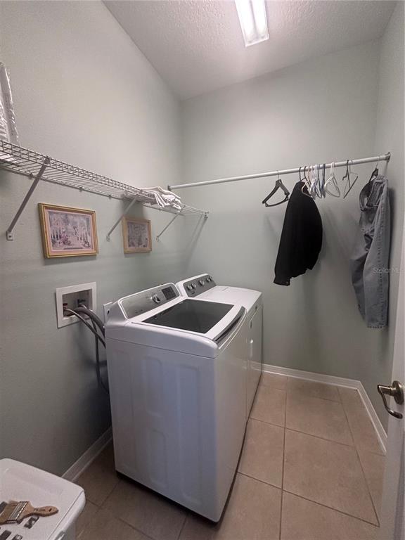 A laundry room features a white washer and dryer, wire shelving, and tile flooring — 818 PECORI TERRACE, OCOEE, FL