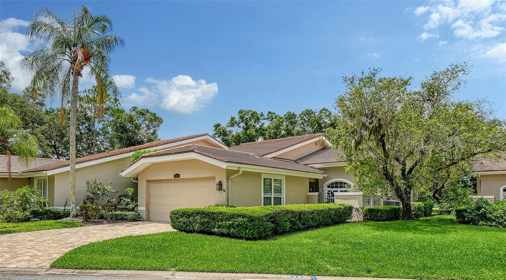 A single-story house with a beige exterior, a two-car garage, and a manicured lawn — 4004 PENSHURST PARK, SARASOTA, FL