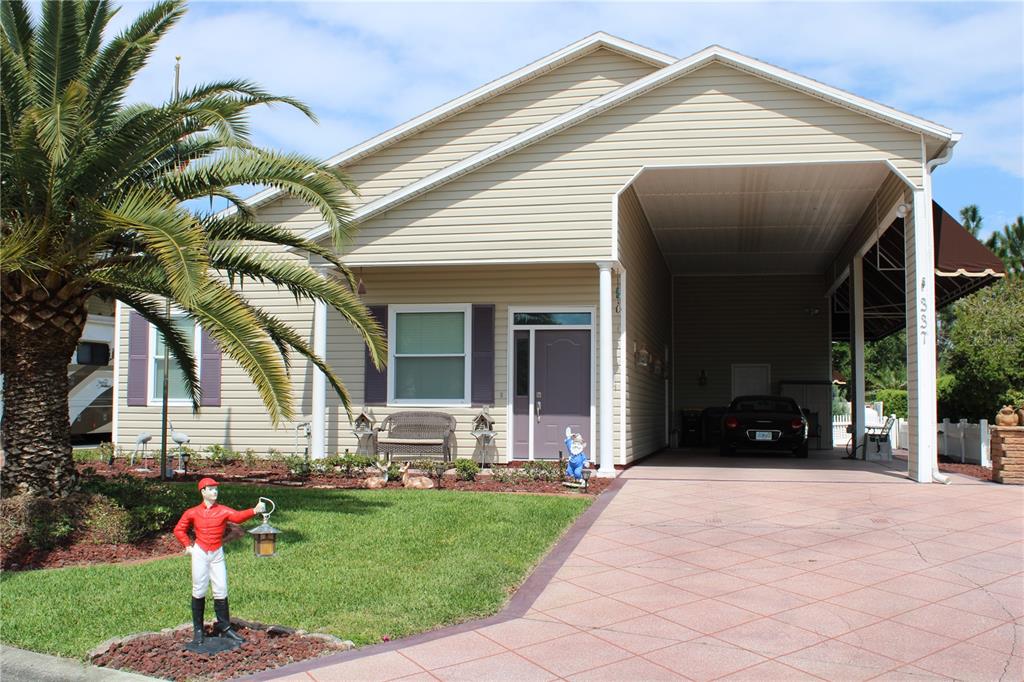 A tan house with a large palm tree, a paved driveway, and a covered carport — 337 MOTORCOACH DRIVE S, POLK CITY, FL
