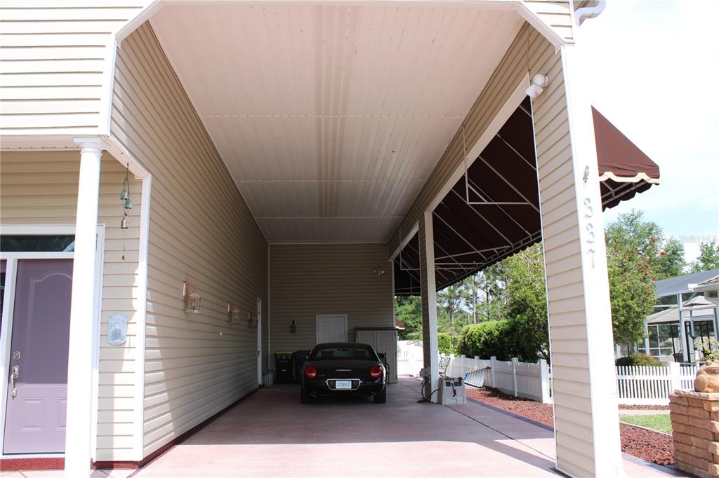 A covered carport with beige siding, a concrete floor, and a parked black car — 337 MOTORCOACH DRIVE S, POLK CITY, FL