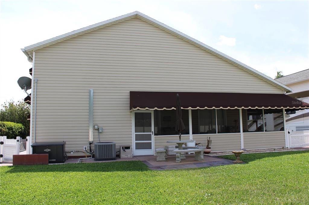 The exterior side of a house features beige siding, a screened patio, and an awning — 337 MOTORCOACH DRIVE S, POLK CITY, FL