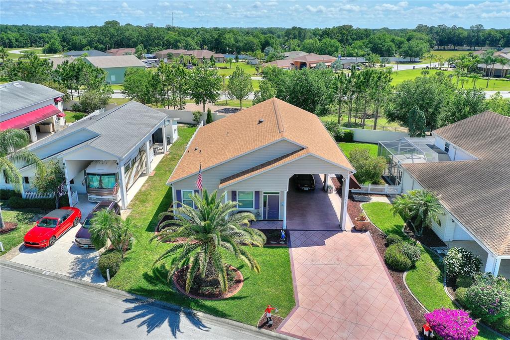 An aerial view shows a suburban house with a tan roof, carport, and palm tree — 337 MOTORCOACH DRIVE S, POLK CITY, FL