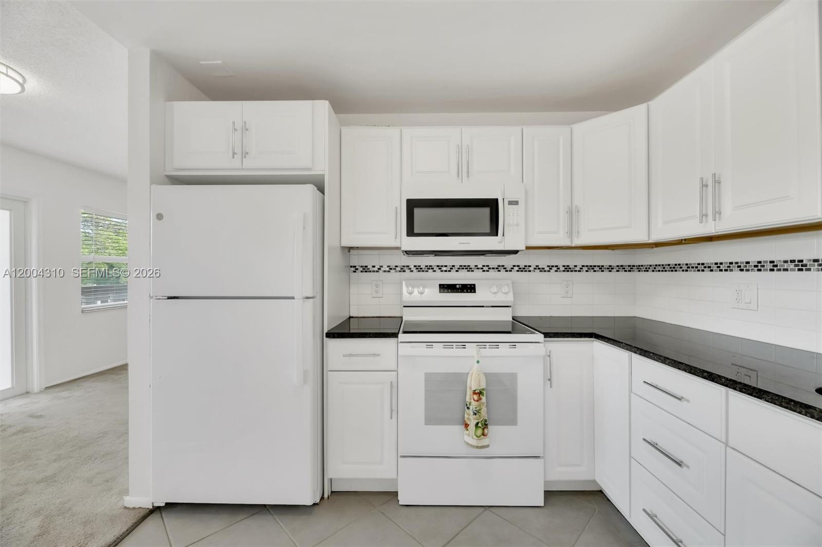 A kitchen features white cabinets, a white refrigerator, a white stove, and black countertops — 3013 Ventnor G # 3, Deerfield Beach FL 33442, DEERFIELD BEACH, FL