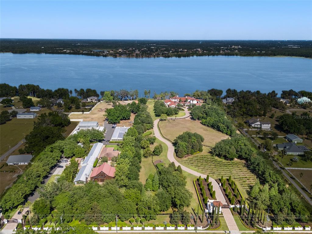 An aerial view shows a large waterfront estate with a long driveway, vineyard, and outbuildings — 11865 FORT KING HIGHWAY, THONOTOSASSA, FL